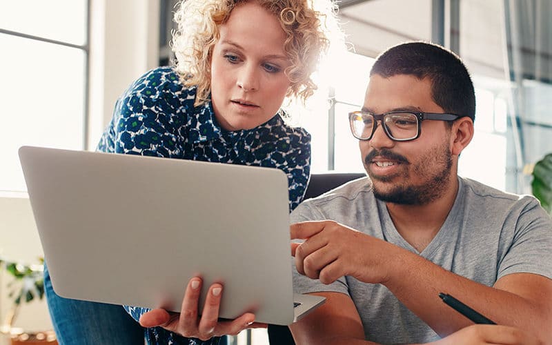 Homem e mulher olhando e apontando para a tela de um notebook